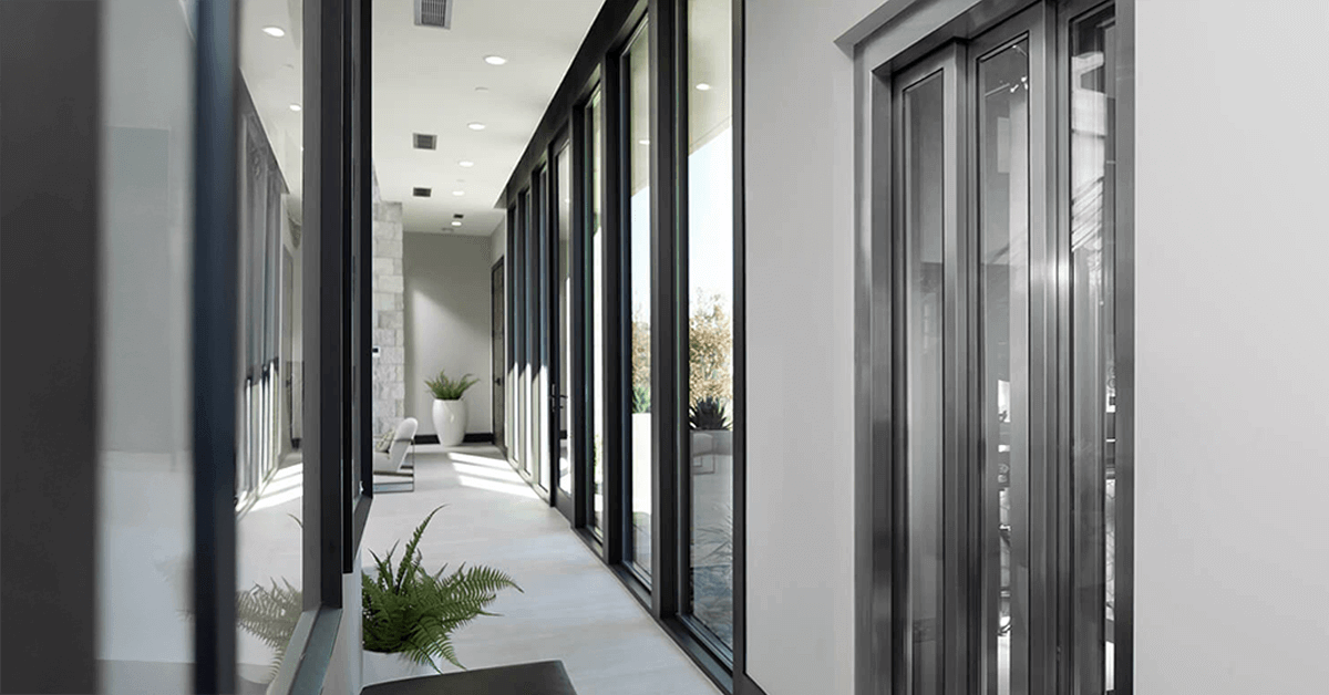 Interior view of a modern building hallway with a residential lift or commercial LU/LA elevator system featuring large, sleek glass doors, emphasizing modern design and professional installation.