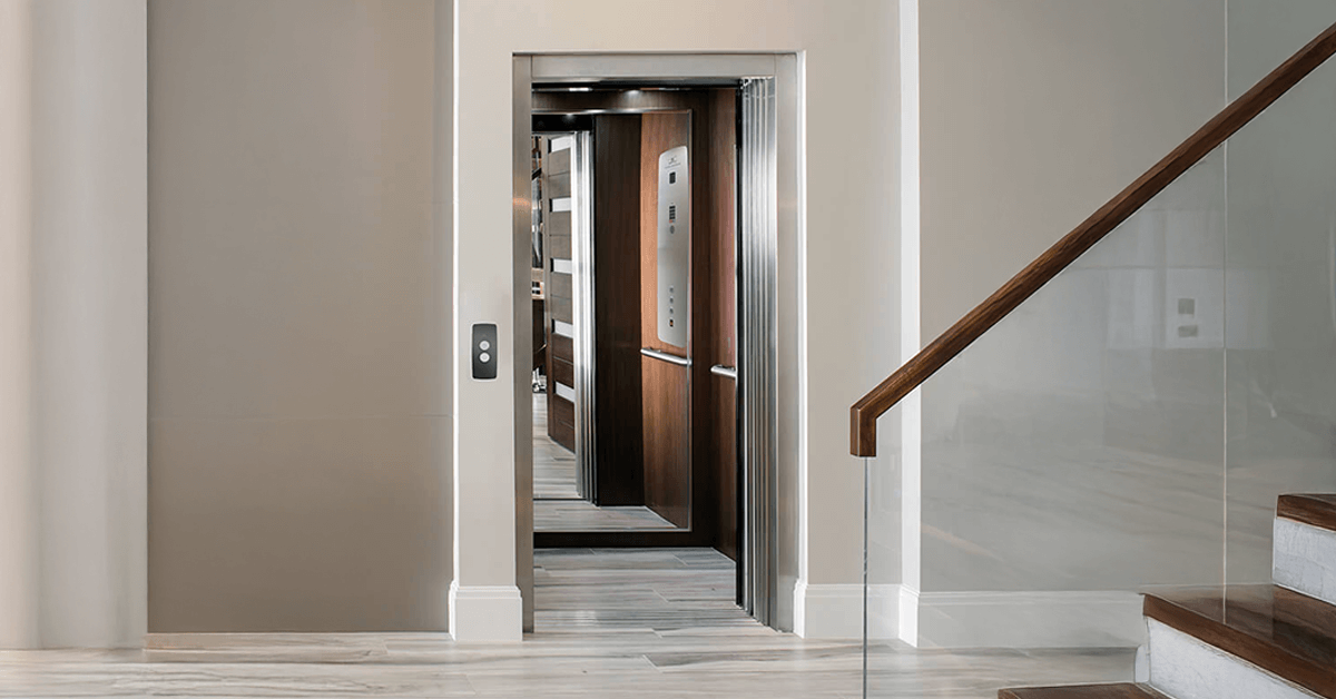 Interior view of a modern North Texas residence hallway showing an open home elevator door with a wood-paneled cab, adjacent to a staircase with a glass railing, demonstrating the seamless integration of a residential lift.