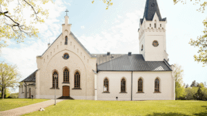 Exterior view of a white traditional church with a steeple and stone walkway, representing Texas houses of worship navigating accessibility standards.