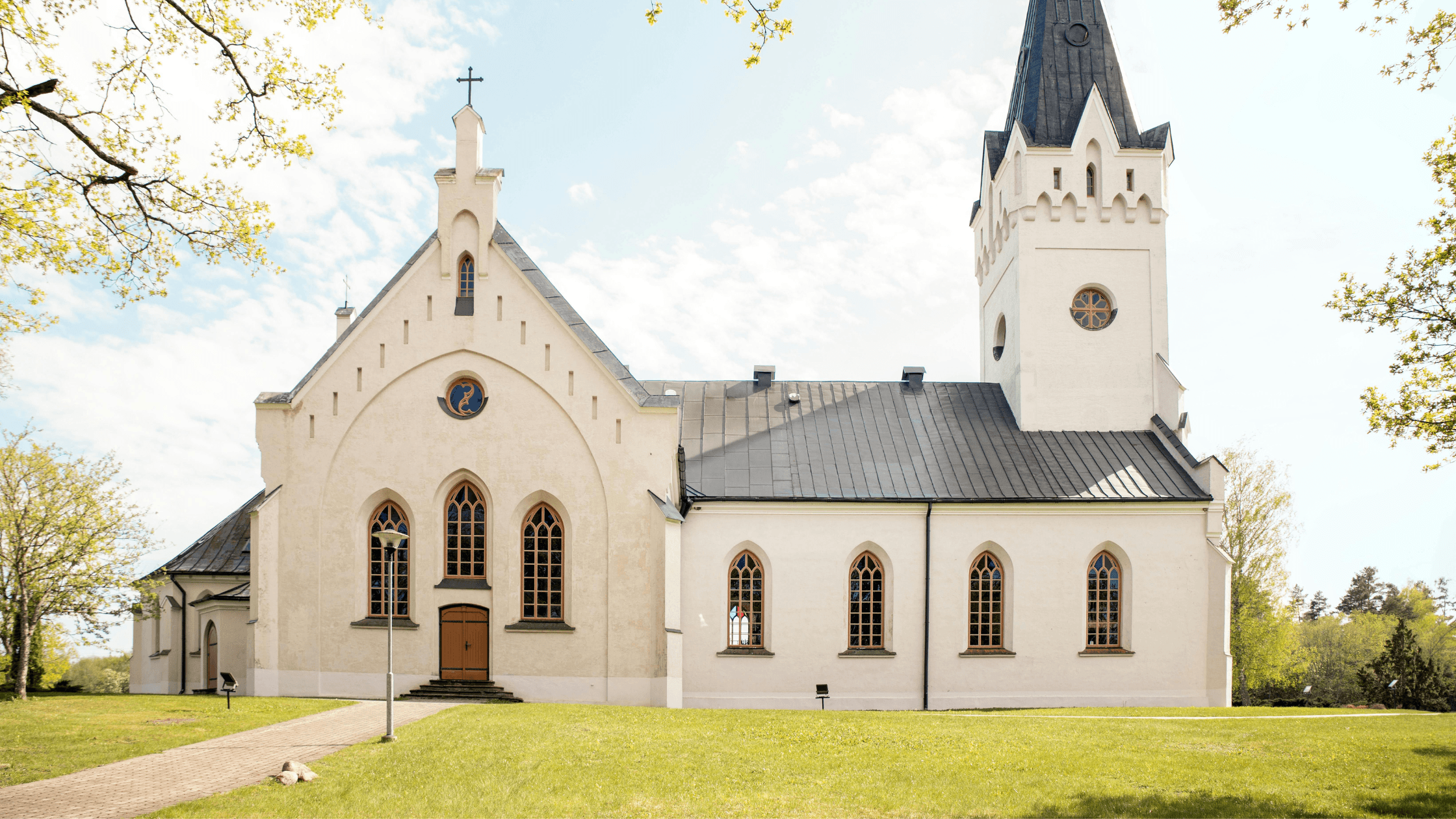 Exterior view of a white traditional church with a steeple and stone walkway, representing Texas houses of worship navigating accessibility standards.